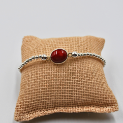 Pulsera elástica de plata con una piedra roja en el centro