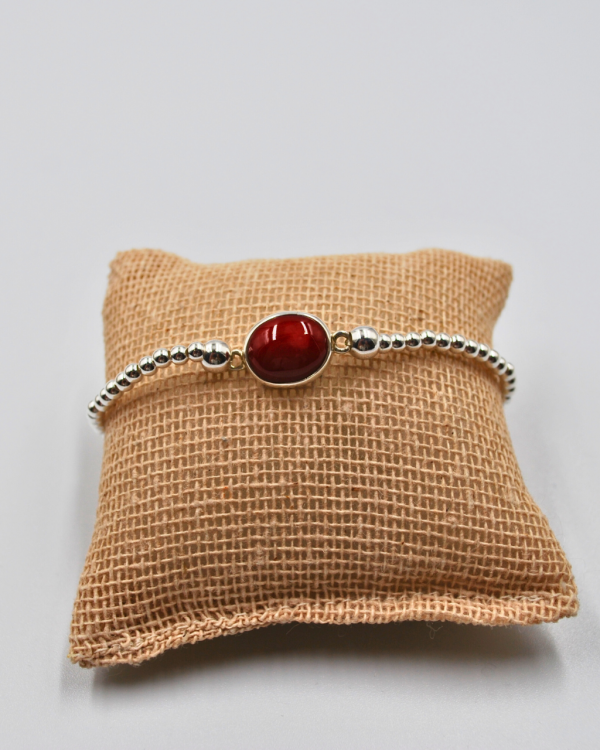 Pulsera elástica de plata con una piedra roja en el centro