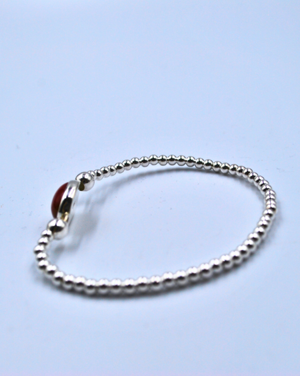 Pulsera elástica de plata con una piedra roja en el centro