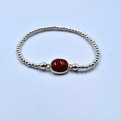 Pulsera elástica de plata con una piedra roja en el centro