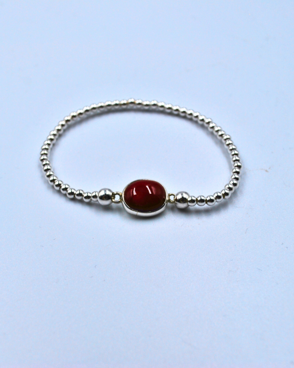 Pulsera elástica de plata con una piedra roja en el centro