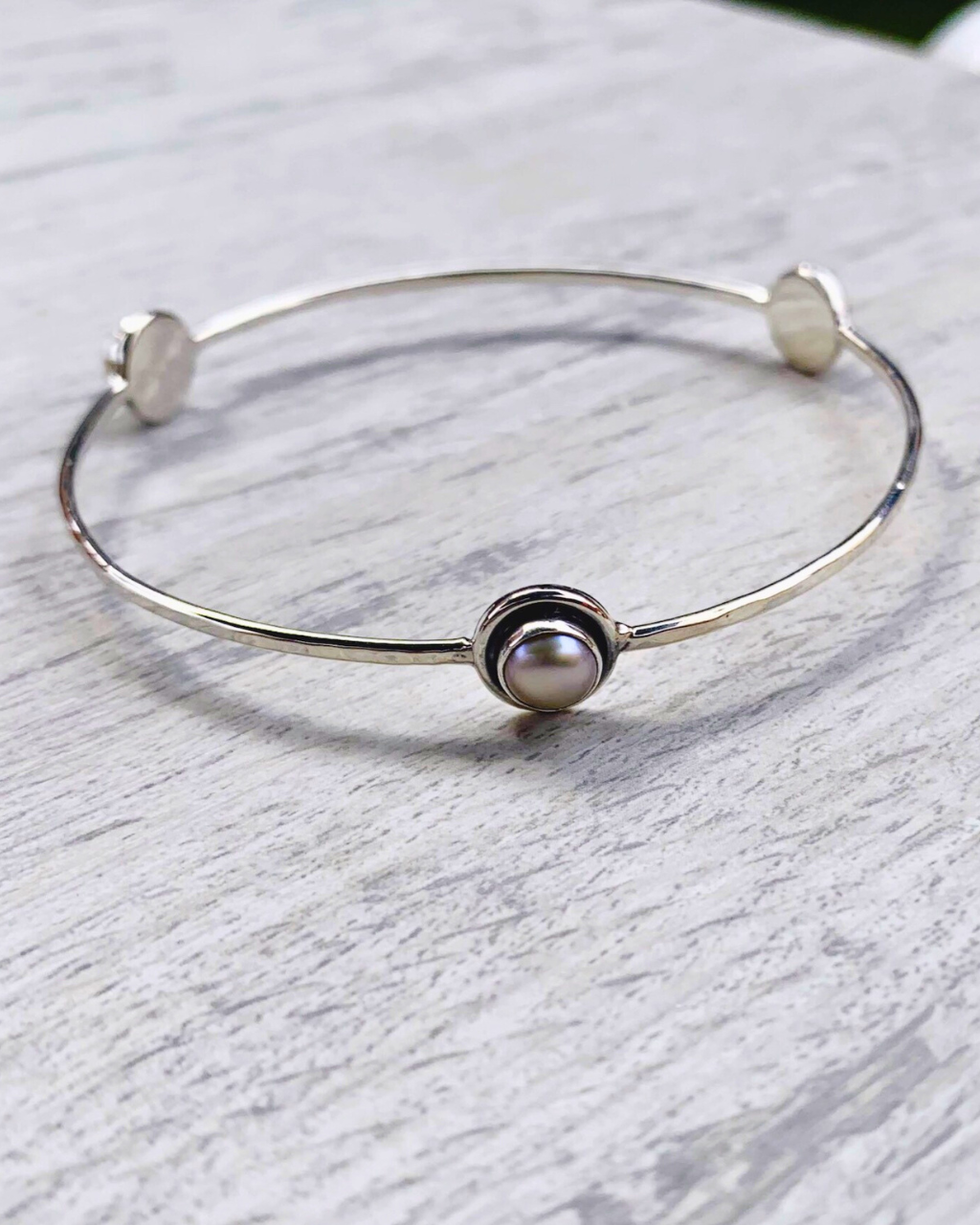 Brazalete de plata con tres perlas decorativas.