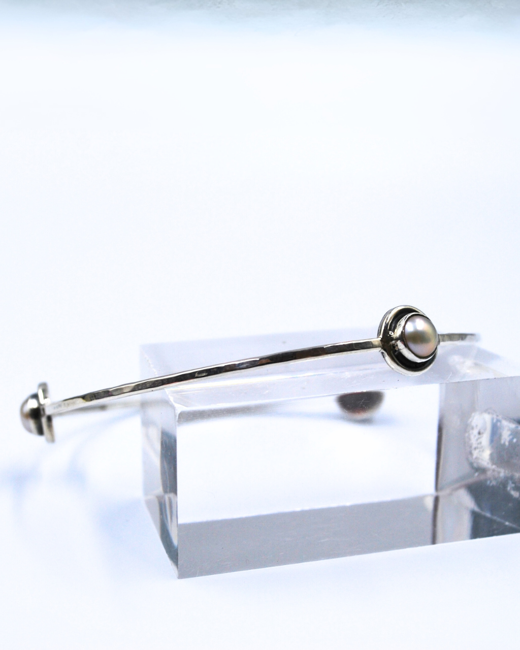 Brazalete de plata con tres perlas decorativas.